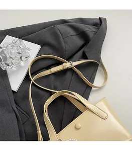 Dettaglio borsa a secchiello in pelle beige con catena di perle e tracolla regolabile