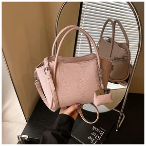 Detail of pink lychee grain leather bucket bag with silver hardware and mini charm