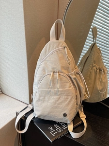 Minimalist beige nylon backpack with multiple zipper pockets and side drawstring compartments