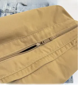 Detail shot of khaki plaid fabric and smooth metal zipper on this casual shoulder bag