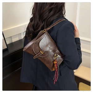 Detail of retro brown leather saddle bag with white contrast stitching and gold buckle