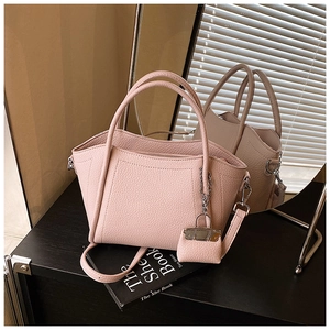 Detail of pink lychee leather handbag with a matching mini charm and detachable strap