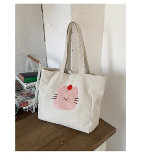 Détail de la texture velours côtelé et de la broderie de dessin animé sur le sac cabas