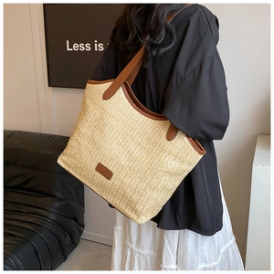 Détail d'un grand sac cabas en paille avec anses en cuir marron et texture tissée