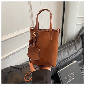 Detailed view of a brown faux leather tote bag featuring a cute dog charm and logo