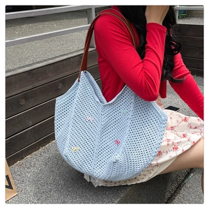 Detail of light blue woven tote bag with colorful butterfly bows and leather shoulder strap