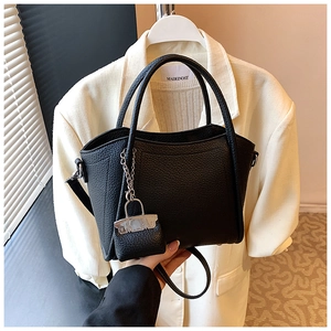 Detail of black pebble leather handbag with silver lock charm and adjustable shoulder strap