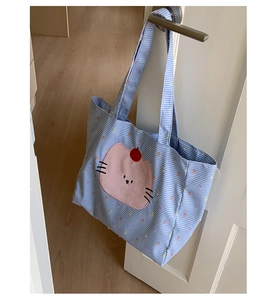Détail du sac cabas vichy bleu avec broderie chat rose sur une texture en coton doux