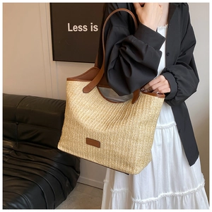 Detailed woven tote bag with brown faux leather handles worn by a model for daily use