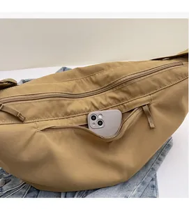 Detail view of khaki nylon crossbody bag featuring a front zipper pocket for smartphones