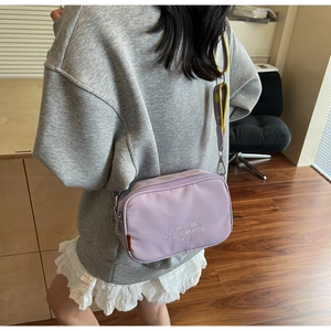Detail of lavender canvas camera bag with New Dreams embroidery and adjustable strap