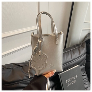 Close-up of a silver mini bucket bag with glossy finish and cute puppy charm accessory