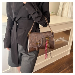Macro detail of a vintage brown leather saddle bag with white contrast stitching
