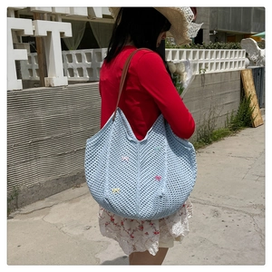 Close-up of light blue hand-woven tote bag with colorful bows and brown leather straps