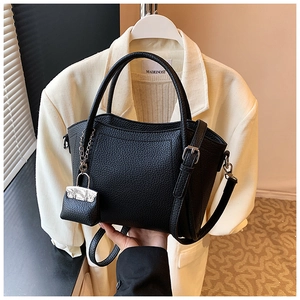 Detail of black litchi grain leather bucket bag with silver hardware and a mini pouch charm