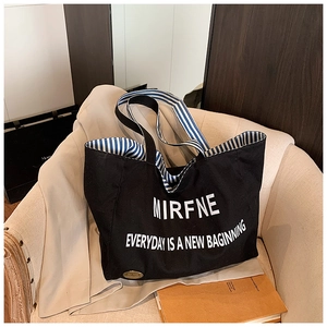 Detail of black canvas tote featuring white art text and blue striped lining interior