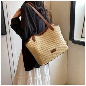Detail of woven tote bag with brown leather handles and fashion label for commute