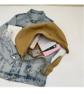 Detailed view of spacious interior of tan canvas crescent bag with daily essentials