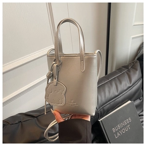 Close-up of silver mini tote bag with dog charm and detachable shoulder strap detail