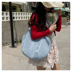 Blue hand-knitted tote bag featuring colorful bow appliques and brown shoulder straps