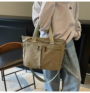 Detail of khaki green nylon tote bag featuring dual front zipper pockets and durable handle