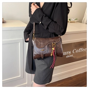 Close-up of vintage brown saddle bag with metal buckle and woven key charm detail