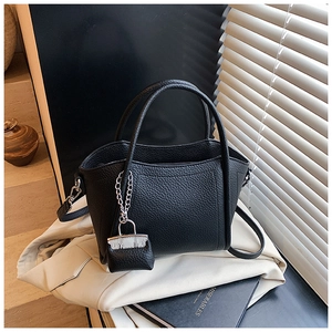 Detail of black lychee grain leather bucket bag with mini charm and silver hardware