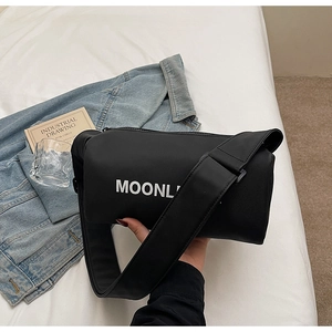 Detail of black nylon cylinder bag featuring white MOONL print and wide strap