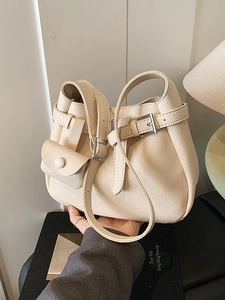 Minimalist beige pebble leather bucket bag with silver buckles and a mini coin pouch