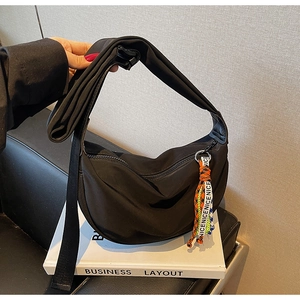 Detail of black crescent crossbody bag with rainbow tassel and durable nylon fabric texture