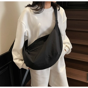 Detail of minimalist black crescent shoulder bag with wide strap on model