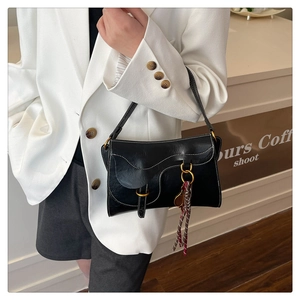 Detail of black leather saddle bag with white contrast stitching and gold ring buckle