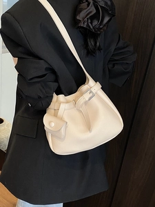 Cream leather bucket bag with pebble texture, silver buckle, and small pouch on model