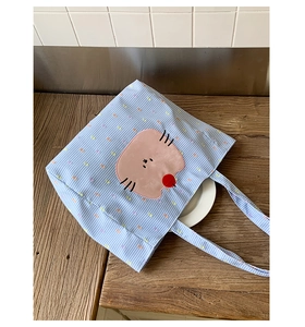 Détail du sac cabas à carreaux bleus avec broderie chat rose et petit pompon rouge