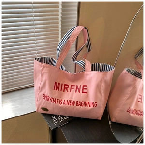 Close-up of pink canvas tote bag showing striped lining and elegant metal detail