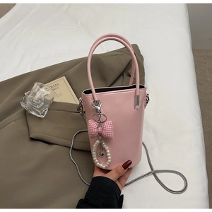 Detail der hellrosa Leder-Eimertasche mit Schleife und Perlenanhänger für Damen