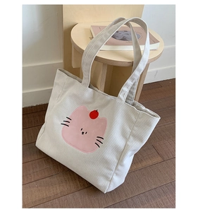 Détail du sac cabas en velours côtelé blanc avec imprimé chat rose sur un tabouret