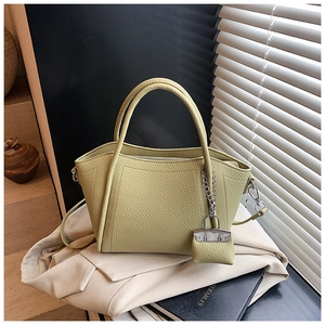 Detail of avocado green litchi texture handbag with silver chain and mini bag charm