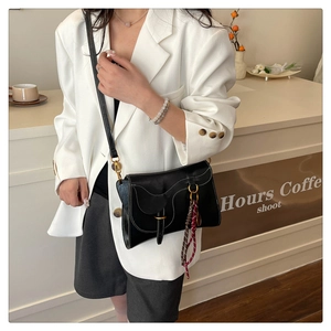 Detail of black leather saddle bag with white stitching and decorative braided rope