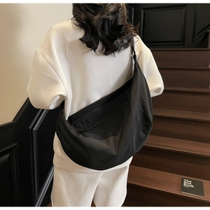 Model view of large black crescent crossbody bag paired with white casual outfit
