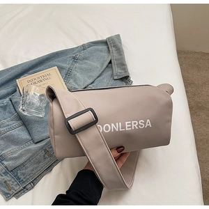 Detail of canvas pillow bag with wide strap and DONLERSA logo in casual setting