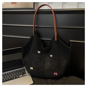 Close-up of black crochet tote bag with colorful 3D bows and brown leather straps