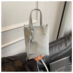 Detail of light blue mini bucket bag with small bear charm and shoulder strap