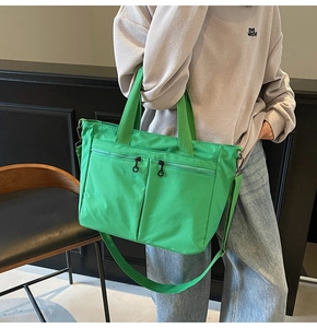 Detail of bright green tote bag featuring multiple zipper pockets and adjustable strap