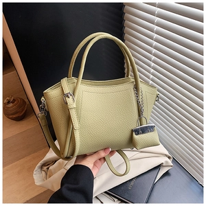 Detail of avocado green litchi grain tote bag with round handle and mini charm