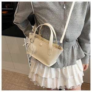 Dettaglio di una mini borsa a secchiello beige con fiocchi di pizzo e perle eleganti
