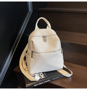 Detail view of the textured twill fabric and silver dual zippers on the beige backpack