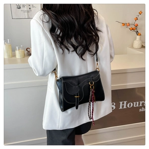 Detail of black saddle bag featuring white contrast stitching and tricolor fringe tassel