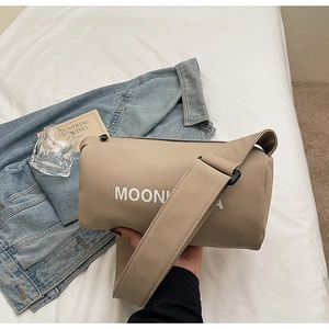 Detailed close-up of beige cylindrical crossbody bag with wide shoulder strap and MOONKA logo