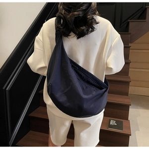 Close-up of minimalist navy nylon crescent bag shown on shoulder in a lifestyle setting